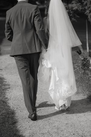 Black and white photos capture the flowing movement of a wedding dress train as couple walks down garden path.