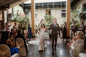 Wedding guests dance and celebrate during an evening reception in an elegant indoor-outdoor venue with string lights.