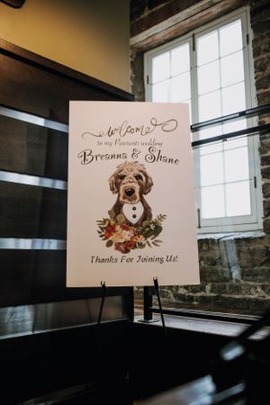 Wedding welcome sign featuring a watercolor illustration of a dog with floral accents.