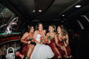A flower girl in a white tulle dress stands beside bridesmaids in burgundy gowns.