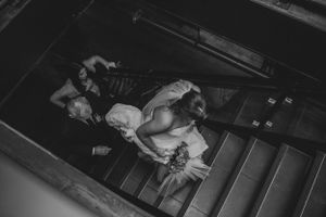 Black and white photo of bride walking down aisle in rustic venue.