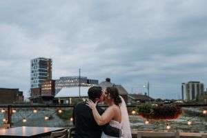 Couple shares an intimate moment against urban cityscape with moody cloudy sky.