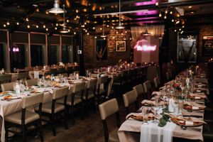 Elegant wedding reception venue with long tables set for dinner under warm lighting.