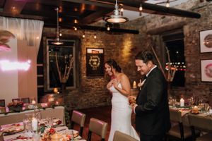 Wedding reception celebration in rustic venue with exposed brick walls and mood lighting.