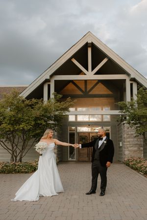 Sequence of wedding couple dancing and twirling outside a modern architectural venue with wooden beams.
