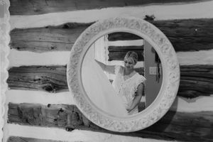 A series of oval-shaped decorative mirrors with ornate frames hang on a rustic wooden wall.