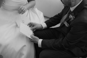Black and white image of a couple seated together looking at documents during their wedding ceremony.
