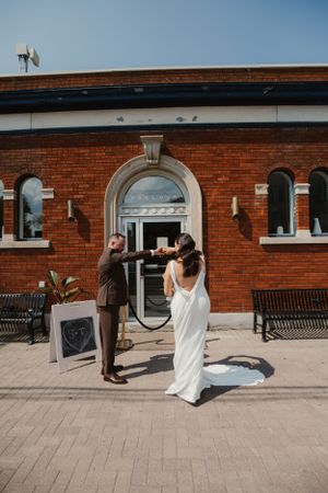 Wedding couple standing outside a historic red brick building with arched windows.