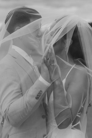 An intimate black and white photo of newlyweds sharing a moment under their veils.