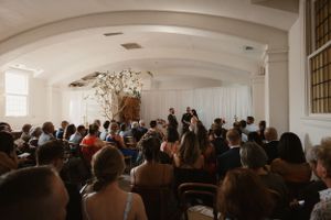 Wedding ceremony venue with white draped walls and rows of seated guests.