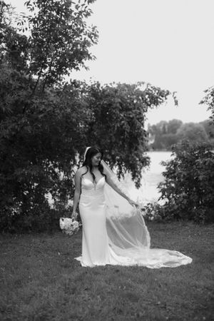 Bride in flowing white dress posing gracefully in garden setting.