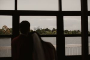 Silhouetted couple looking out large window at waterfront view.