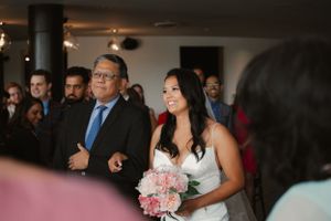 Wedding ceremony moment with bouquet of pink flowers in indoor venue.