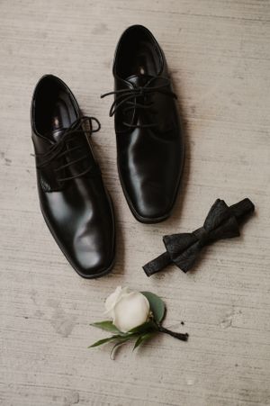 Groom's formal black leather shoes with bow tie and white boutonniere.