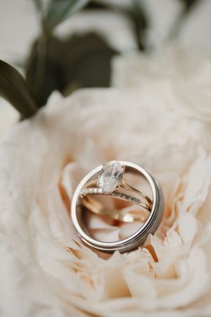 Wedding rings macro shot on soft pink rose petals with diamond engagement ring.