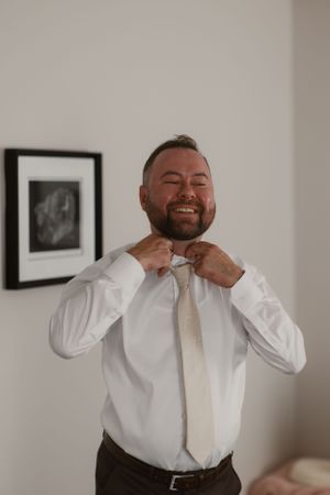 Someone adjusting their necktie while getting ready for a formal occasion.
