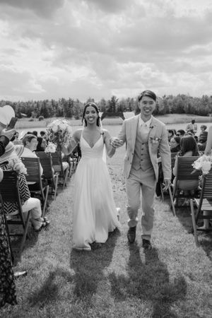 A joyful couple walks down the aisle after their outdoor wedding ceremony.