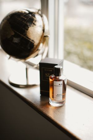 Perfume bottle and vintage globe displayed on windowsill.