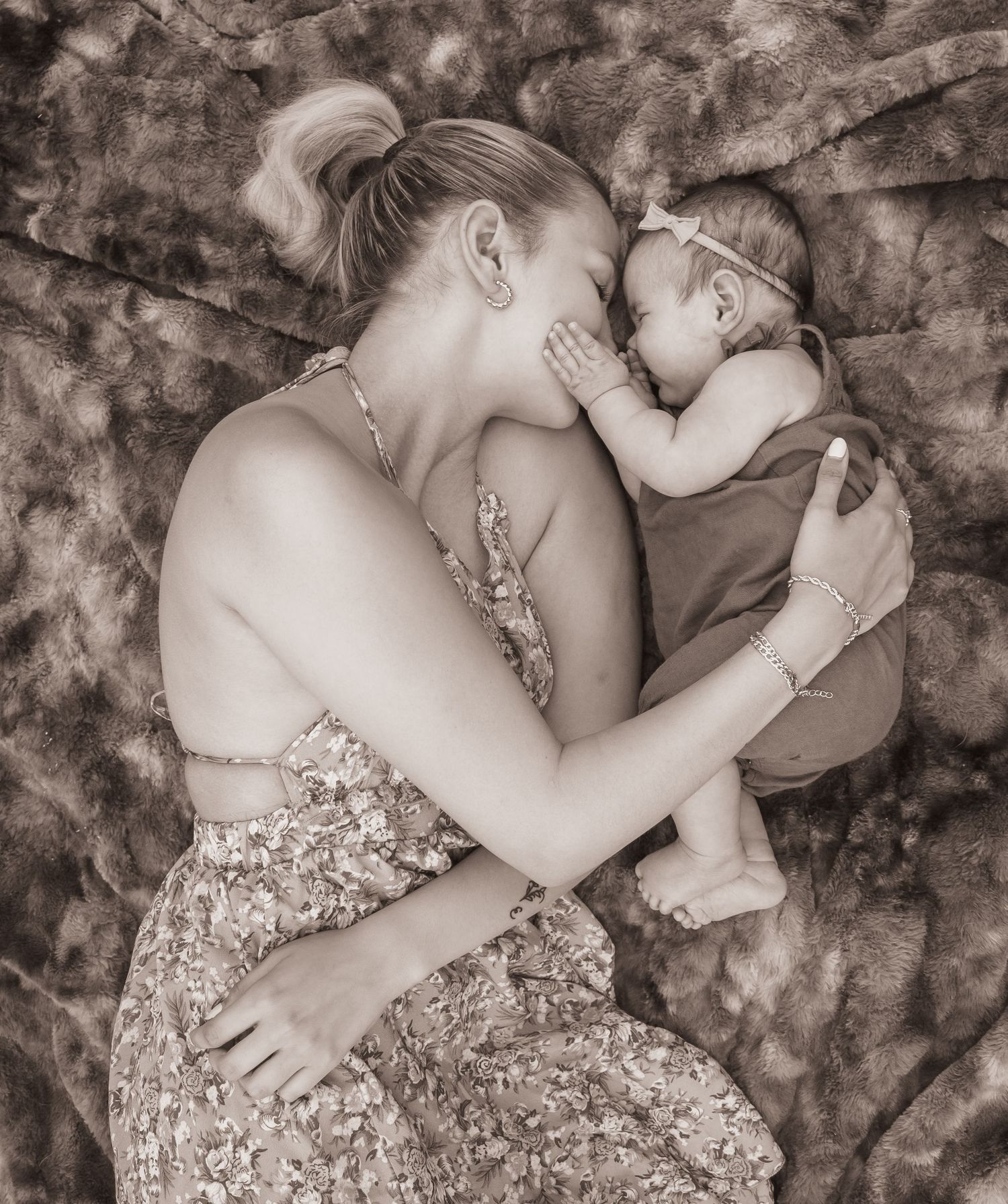 mom and baby girl, lying down on a blanket, face to face, baby touching mom's face, beautiful emotive moment of motherhood