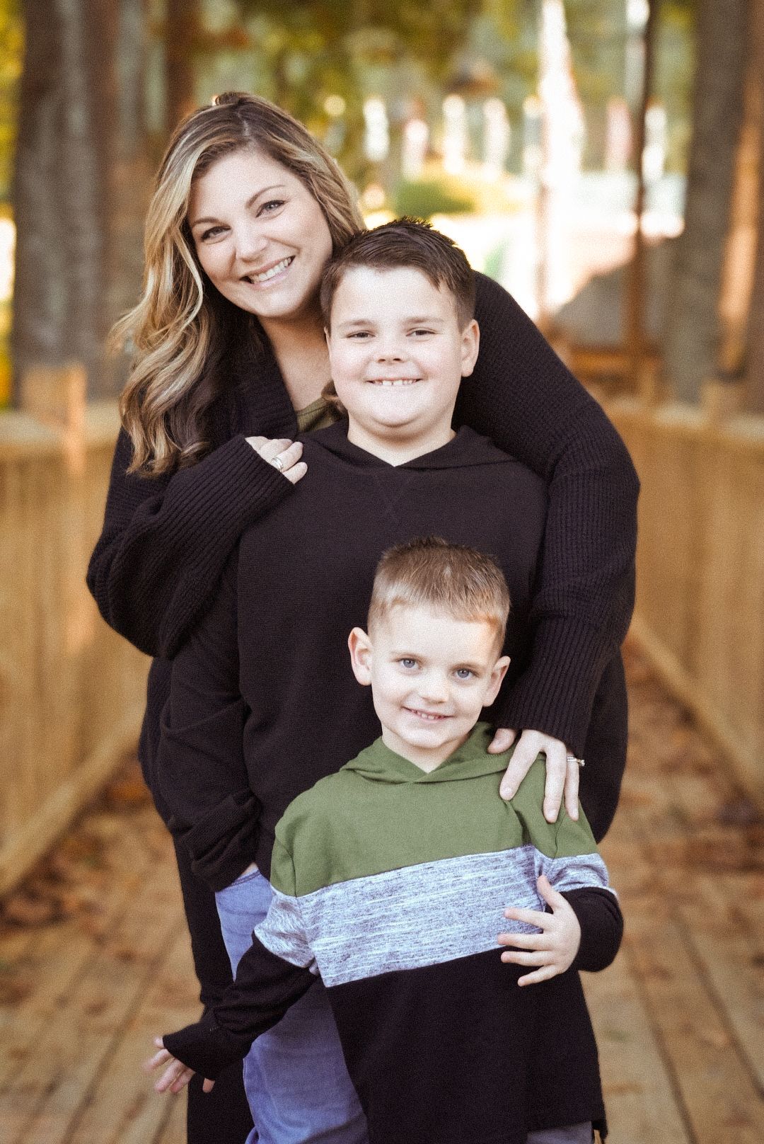 A sequence of warm family portraits taken on a wooden deck surrounded by fall foliage.