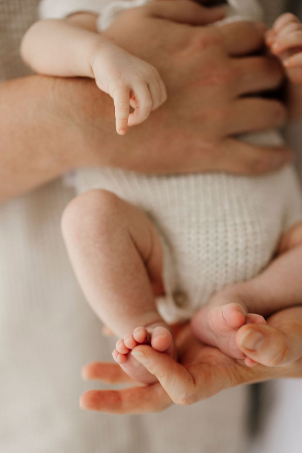 A close-up of a newborn babys tiny feet and hands resting in a parents gentle hands.
