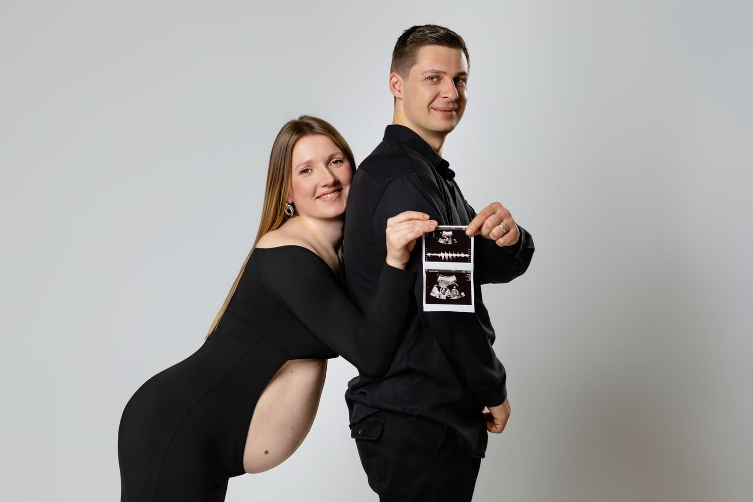 A group of people in black outfits strike playful poses against a white studio backdrop.