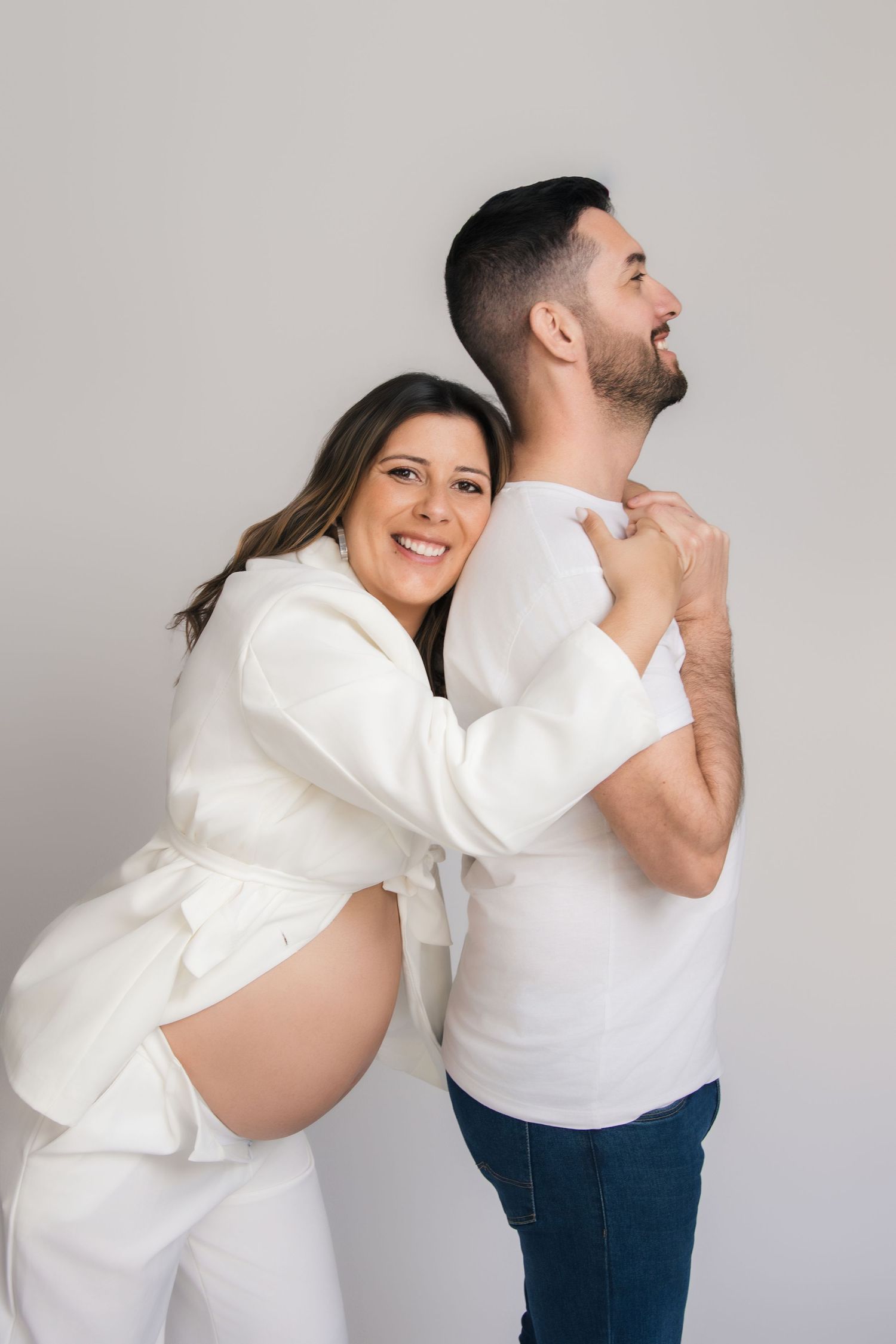 A couple in white and blue outfits poses playfully in a sequence of five connected photos against a gray background.
