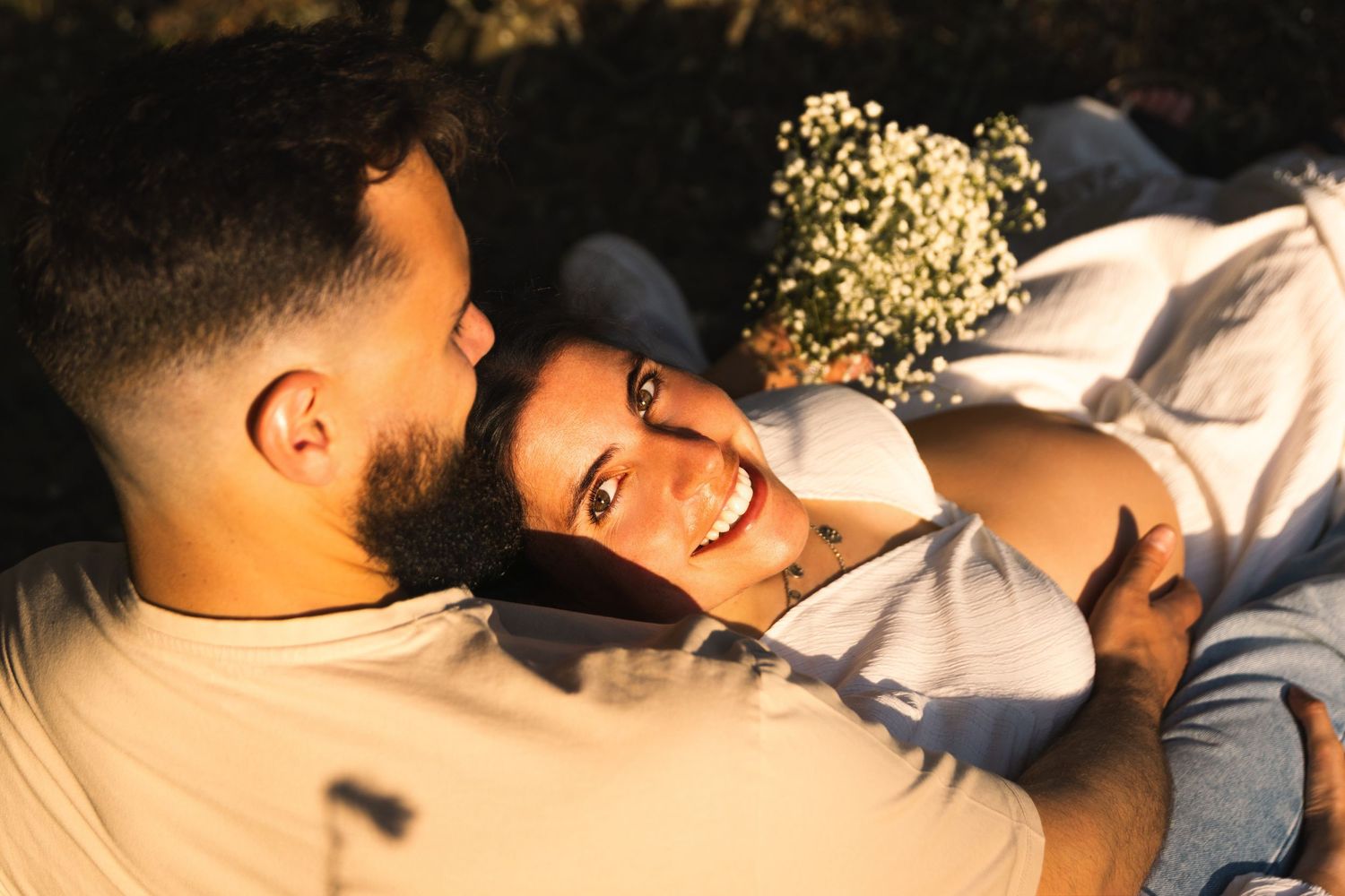 Intimate couple sharing tender moment while lying down at dusk.