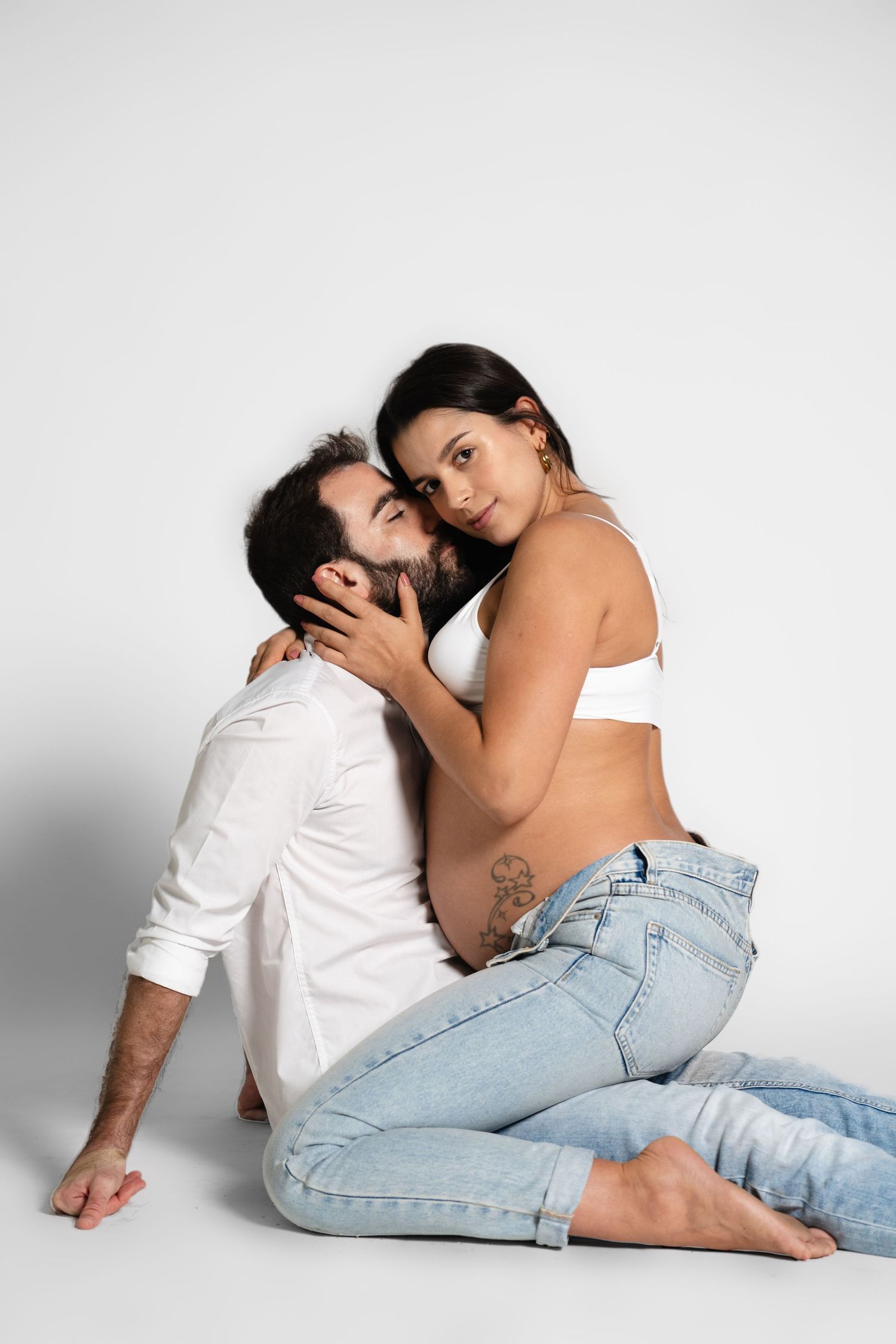 Intimate couple photo session against white studio background.