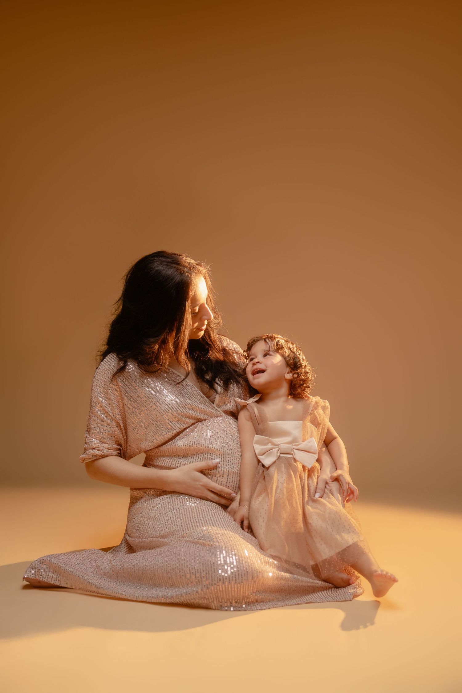 A series of tender mother and child portraits in matching white outfits against a warm brown backdrop.