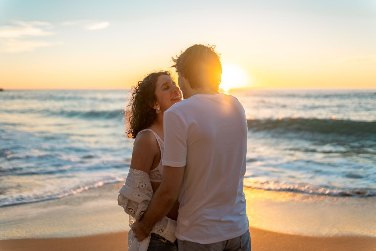 Romantic beach photoshoot silhouettes at sunset with golden light.