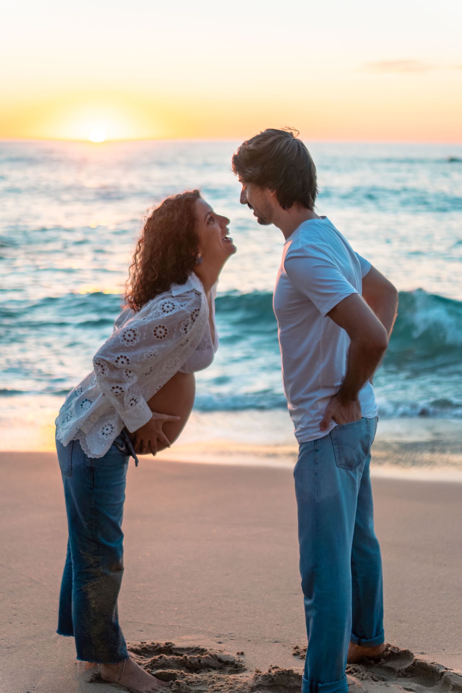 Children playing together on beach at sunset during family photo session.