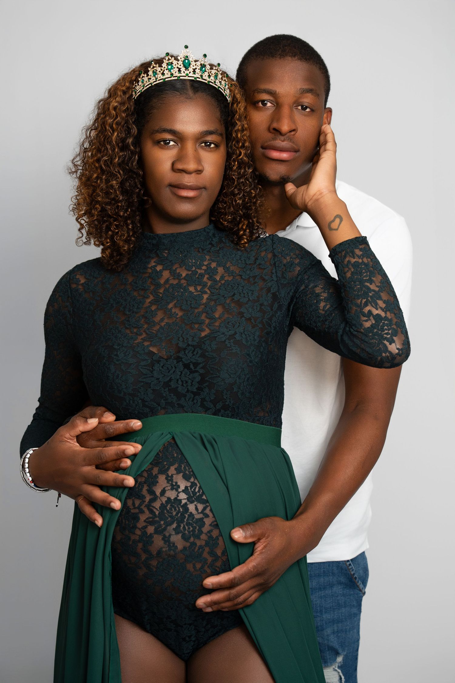 Studio maternity portrait with black lace dress and emerald green fabric.