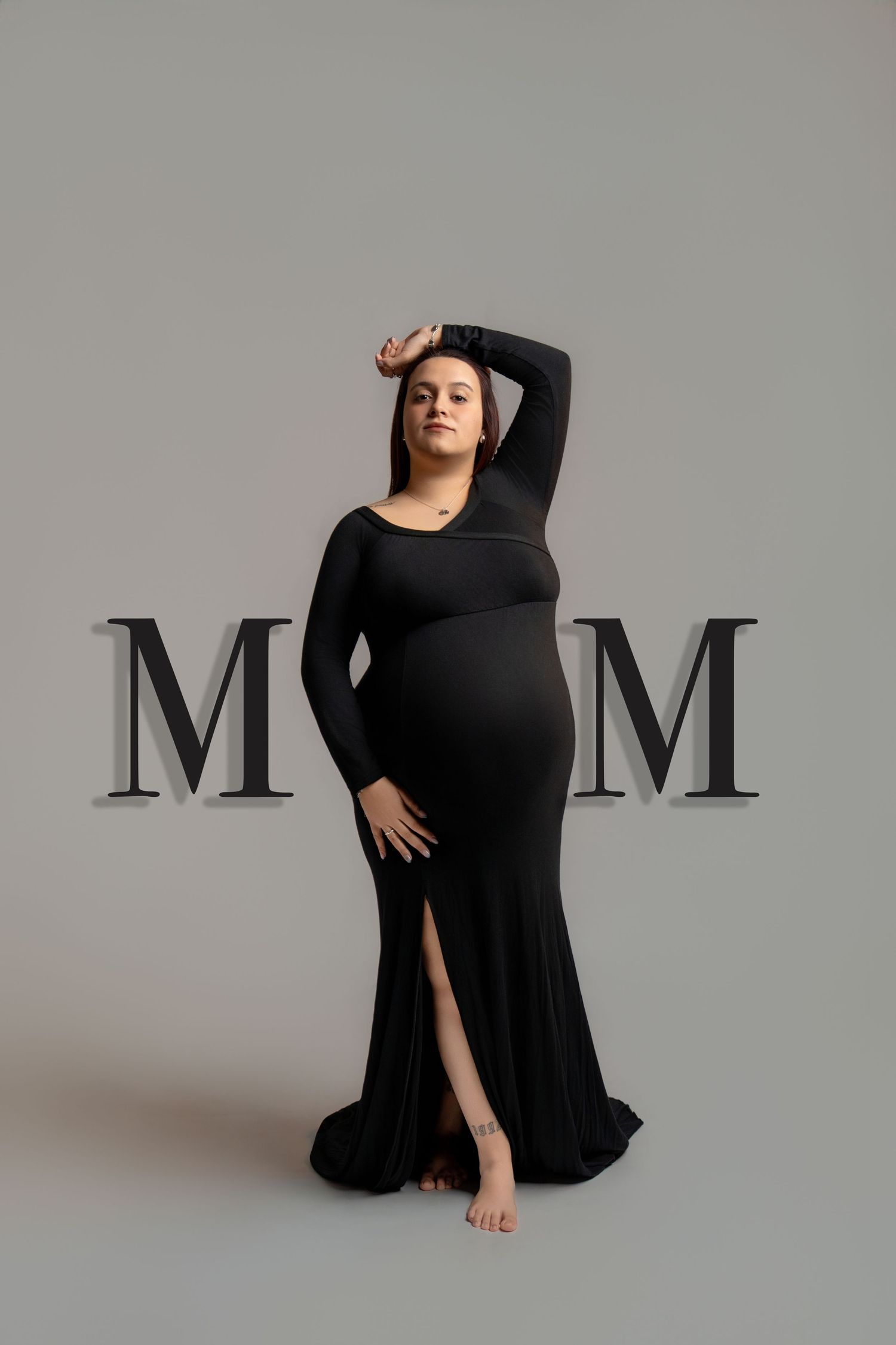 Artistic maternity photo series in black dress against grey background with letter M decor.