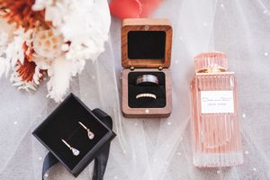 Wedding detail flatlay with perfume bottles and accessories in soft pink tones.