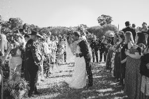 A large gathering of wedding guests outdoors in a natural setting.