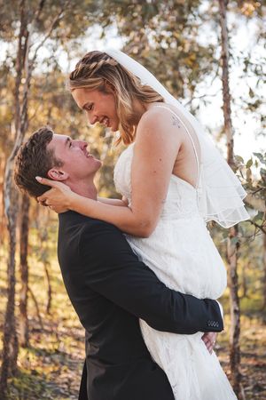 A romantic wedding moment captured in a wooded setting.