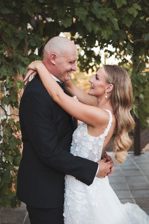 Couple shares joyful dance moment during outdoor wedding celebration.
