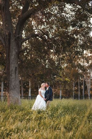 Romantic wedding portraits among tall trees and natural grass fields.