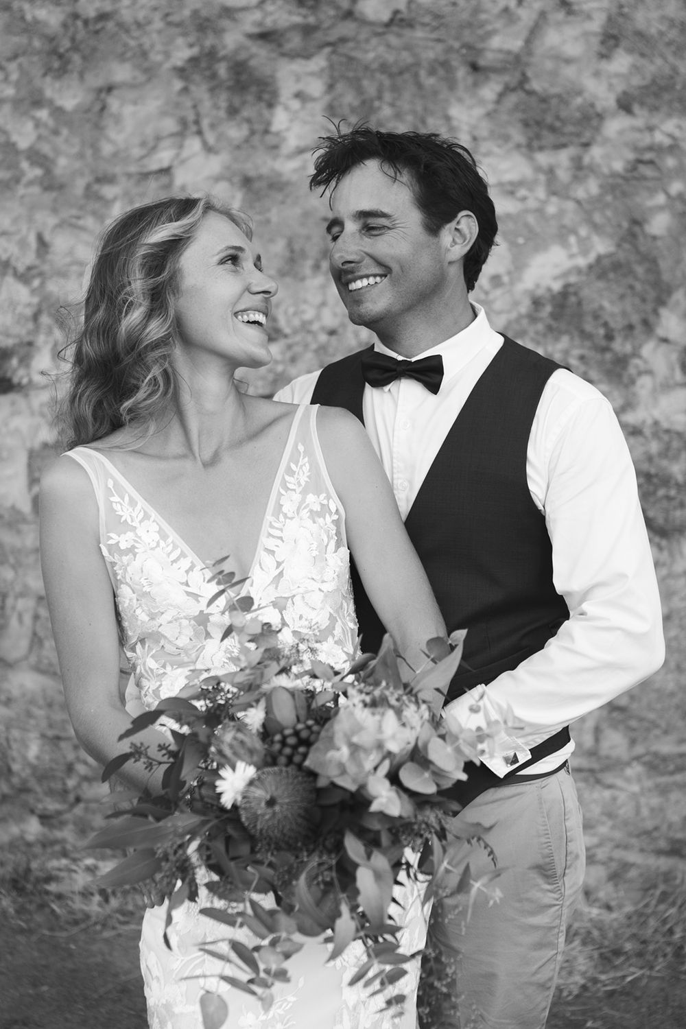 Black and white romantic wedding portraits against stone wall.