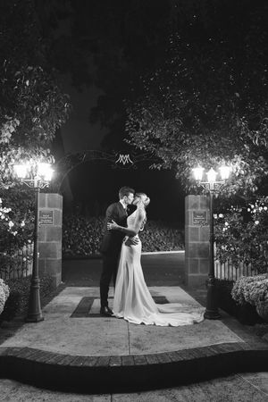 A romantic nighttime portrait illuminated by garden lights on a brick pathway.
