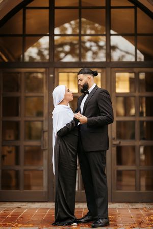 A couple shares a tender moment in a series of romantic poses against a glass window backdrop.