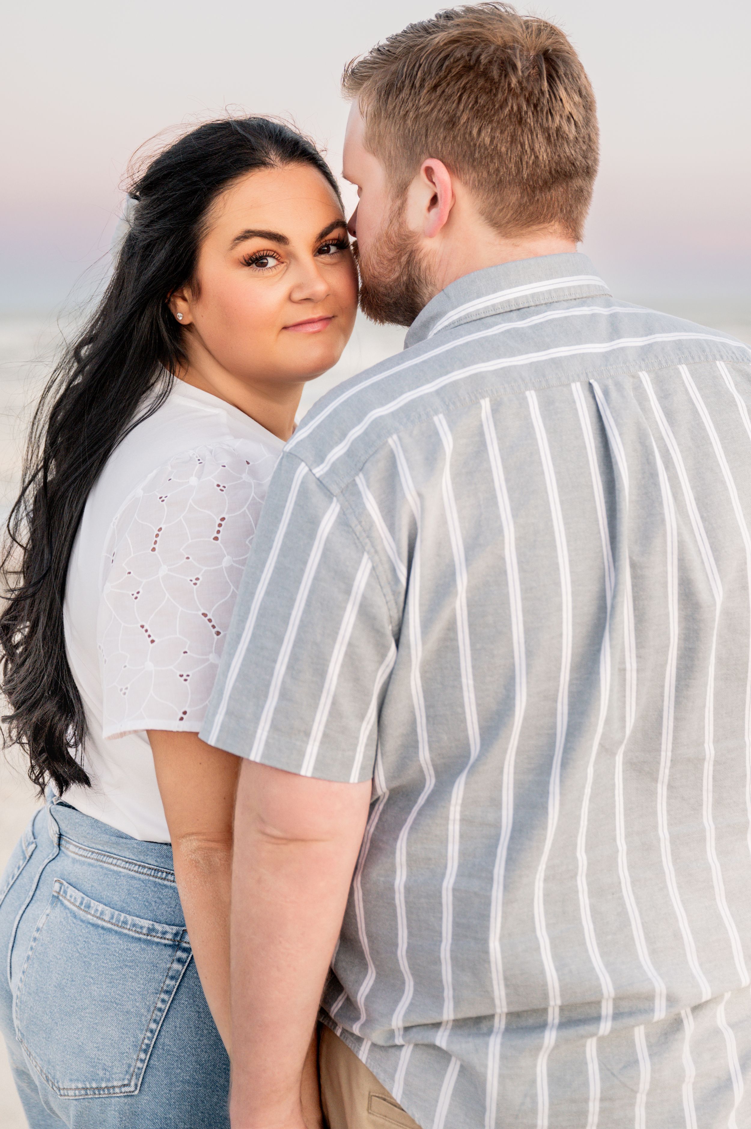 Intimate portraits of couple in striped shirt and denim against soft lighting.