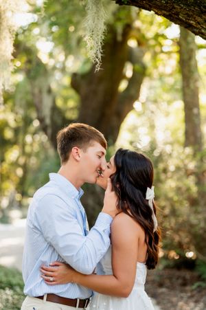 Intimate couple portrait under moss-covered trees in natural setting.
