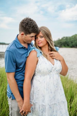 A romantic photoshoot in a coastal marsh setting with tall grass and summer skies.