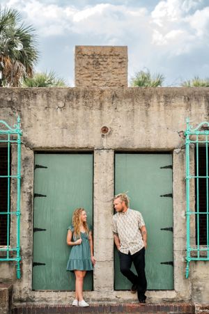 A creative engagement photo series with a couple posing by turquoise-trimmed green doors.