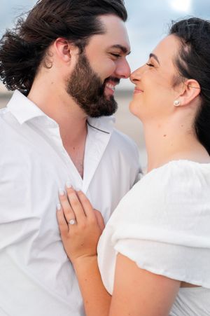 An intimate close-up of a couple in white clothing against a bright background.