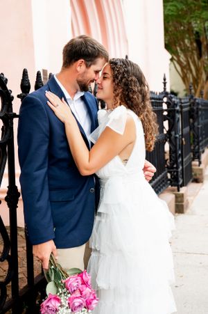 Romantic wedding sequence with couple embracing near decorative iron fence and pink bouquet.
