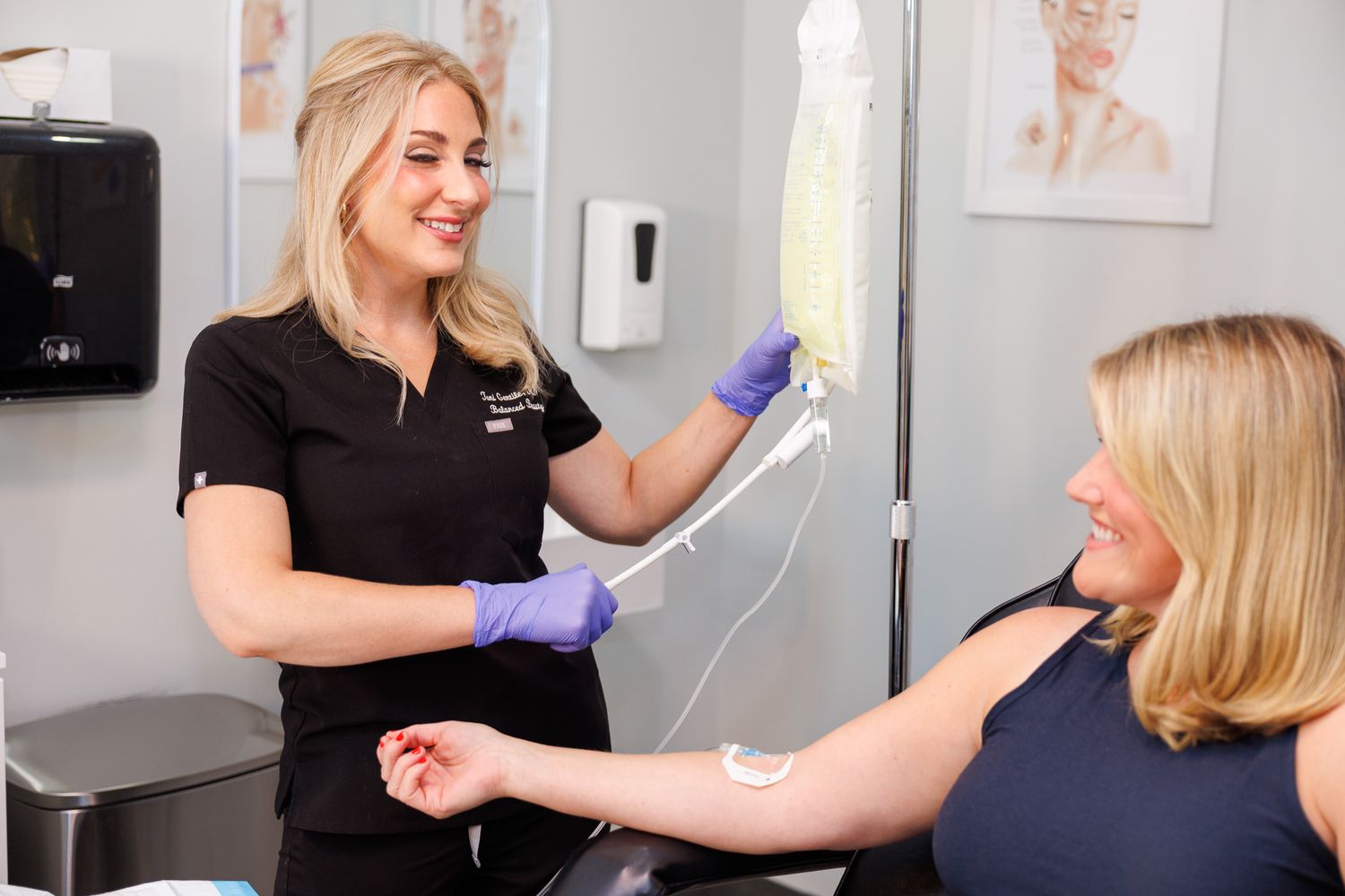 Medical professional in black uniform administering treatment with IV drip in clinical setting.