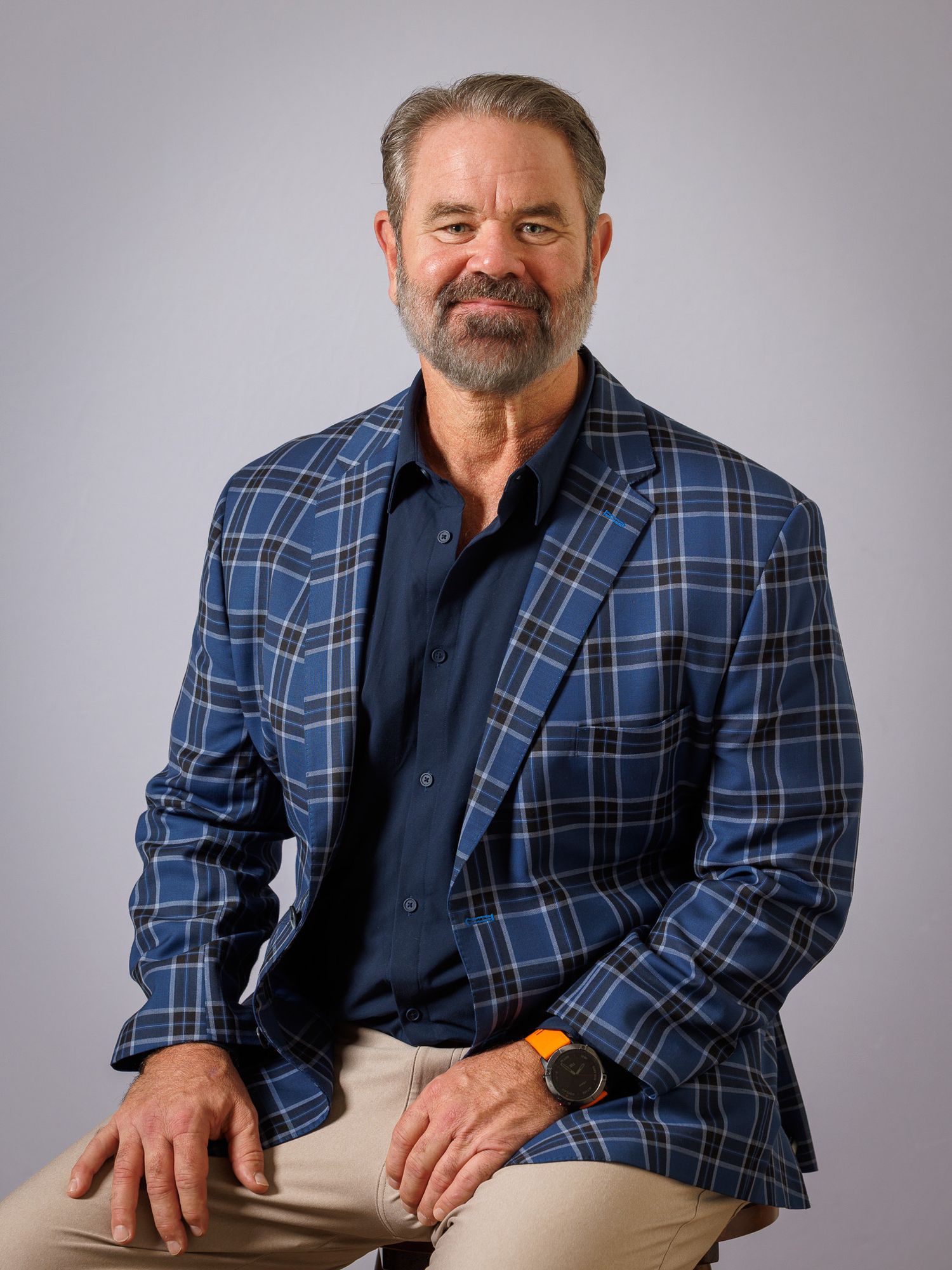 Professional portrait of a person wearing a blue plaid blazer and navy shirt against a neutral background.